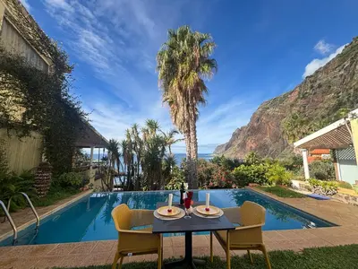 a table and chairs next to a swimming pool at Bela Vigia in Jardim do Mar