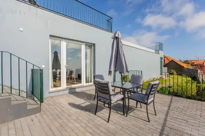 a patio with a table and chairs and an umbrella at Cantinho do Barreiro - Calheta in Calheta