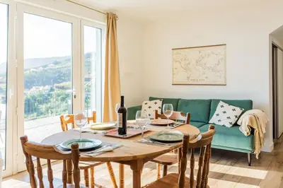 a dining room with a table and a green couch at Cantinho do Barreiro - Calheta in Calheta