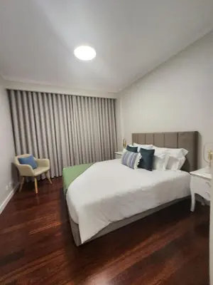 a bedroom with a large white bed and a chair at Blue Diamond-seaview & free park in Funchal