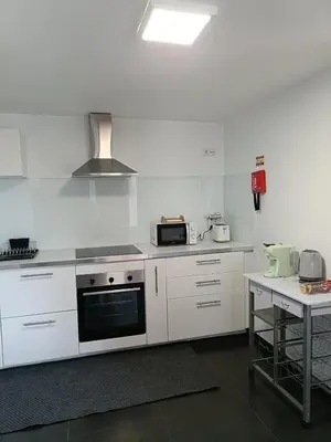 a white kitchen with a stove and a microwave at Ribeira Roots Residence in Santa Cruz