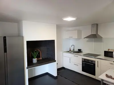 a kitchen with white cabinets and a brick fireplace at Ribeira Roots Residence in Santa Cruz