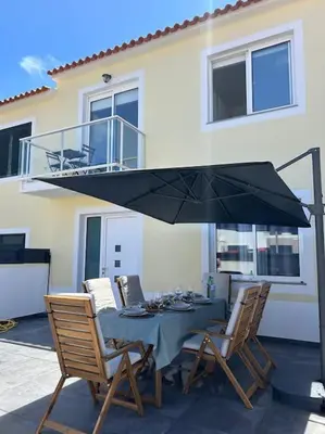 a table with chairs and an umbrella in front of a house at Golden Island in Porto Santo