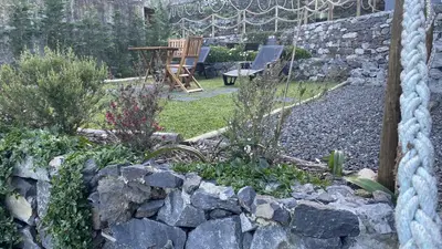 a garden with a stone wall and a chair at Casas das Hortas, Apartamento Vista Serra e Mar in Seixal