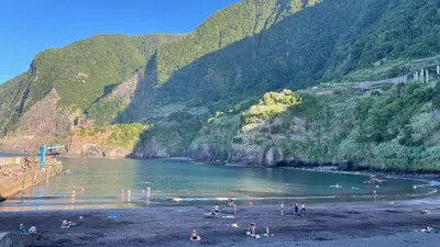 a group of people on a beach next to a mountain at Casas das Hortas, Apartamento Vista Serra e Mar in Seixal