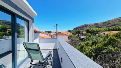 a green chair sitting on the balcony of a house at Casa D'Além I & II by LovelyStay in Machico