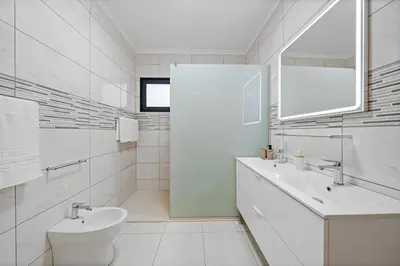 a white bathroom with a sink and a toilet at Calheta Paradise Holiday Home - Free Parking & Views in Arco da Calheta