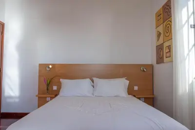 a bedroom with a white bed with a wooden headboard at Casa Menezes Sunrise and Sunset Every Day in Calheta