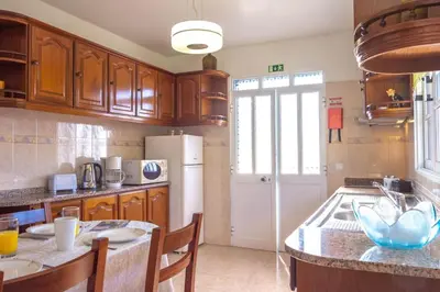 a kitchen with wooden cabinets and a white refrigerator at Casa Menezes Sunrise and Sunset Every Day in Calheta