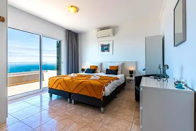 a bedroom with a bed with a view of the ocean at Casa Flora, 2 quartos,vista mar in Arco da Calheta