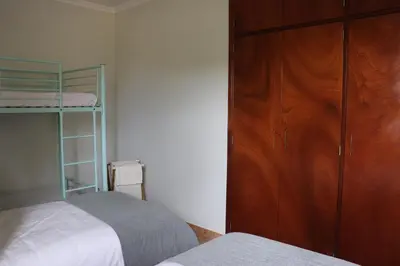 a bedroom with two beds and a wooden cabinet at Pé n' Areia Beach House Porto Santo in Porto Santo