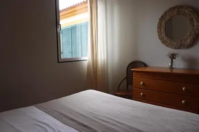 a bedroom with a bed and a dresser and a mirror at Pé n' Areia Beach House Porto Santo in Porto Santo
