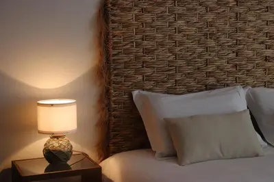 a bedroom with a bed with a lamp on a night stand at Pé n' Areia Beach House Porto Santo in Porto Santo