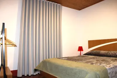 a bedroom with a bed and a window with curtains at Casa da Ponta in Ponta do Pargo