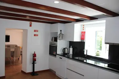 a kitchen with white cabinets and a black counter top at Casa da Ponta in Ponta do Pargo