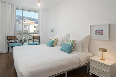 a white bed with blue pillows in a bedroom at The Plaza Apartment in Funchal