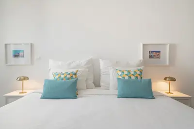 a bedroom with a large white bed with blue pillows at The Plaza Apartment in Funchal