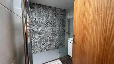 a bathroom with a shower with a black and white tile wall at Marialina, By OP in São Vicente