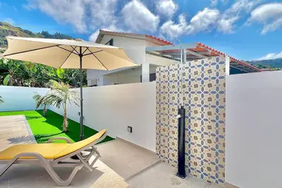 a patio with a yellow chair and an umbrella at A Casa Azul - Arco da Calheta in Arco da Calheta