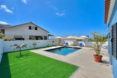 a backyard with a swimming pool and green grass at A Casa Azul - Arco da Calheta in Arco da Calheta