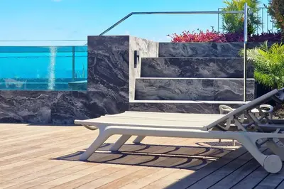 a bench sitting on a deck next to a swimming pool at Empire Luxury Suite - Savoy Insular in Funchal