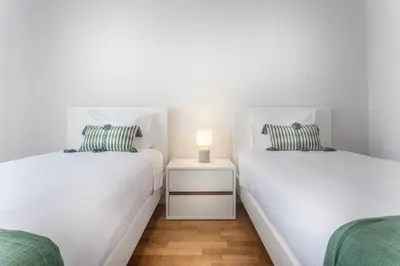 two twin beds in a bedroom with a lamp on a night stand at Jango Paradise in Funchal