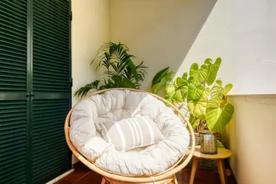a wicker chair sitting in a room with plants at Machico Fachos View, a Home in Madeira in Machico
