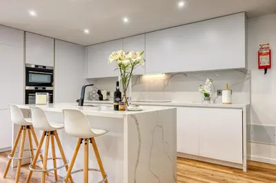 a kitchen with white cabinets and a counter with stools at Machico Fachos View, a Home in Madeira in Machico