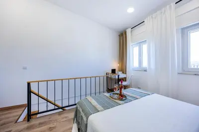 a white bedroom with a bed and a window at Casa Clara in Vila do Bispo