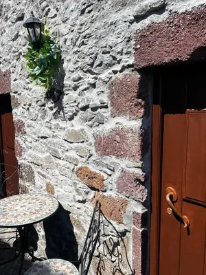 a table and chairs next to a stone wall at Palheiro Mar by Olá Madeira in Paul do Mar