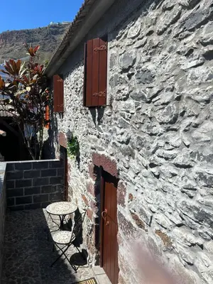 a stone building with a table next to a door at Palheiro Mar by Olá Madeira in Paul do Mar