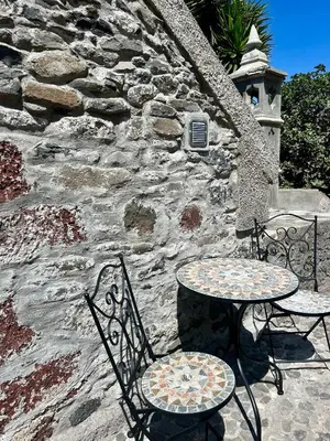 a table and two chairs sitting next to a stone wall at Palheiro Jardim by Olá Madeira in Paul do Mar
