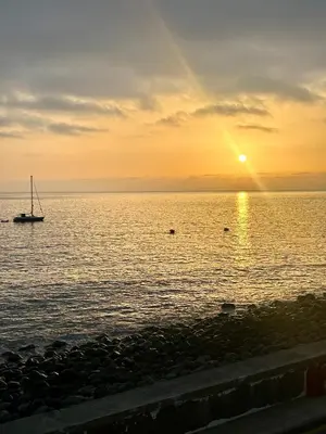 a sail boat in the ocean at sunset at Palheiro Jardim by Olá Madeira in Paul do Mar