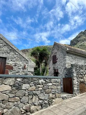 a stone building with a stone wall and a palm tree at Palheiro Jardim by Olá Madeira in Paul do Mar