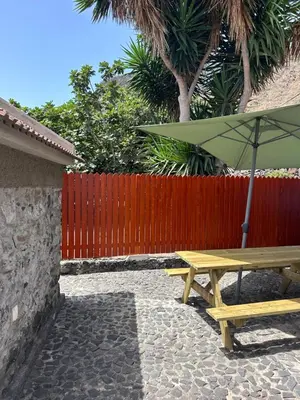 a wooden picnic table with an umbrella next to a fence at Palheiro Jardim by Olá Madeira in Paul do Mar