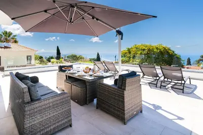 a patio with a table and chairs and an umbrella at El Dourado House in Caniço