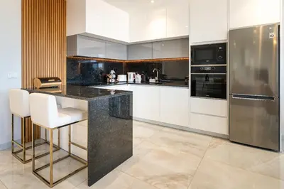 a kitchen with white cabinets and stainless steel appliances at El Dourado House in Caniço