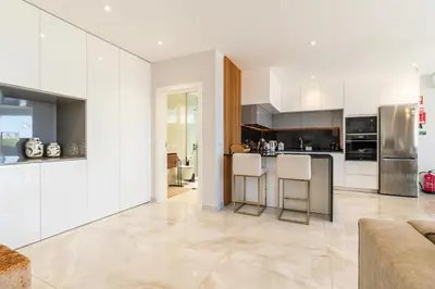 a kitchen with white cabinets and stainless steel appliances at El Dourado House in Caniço