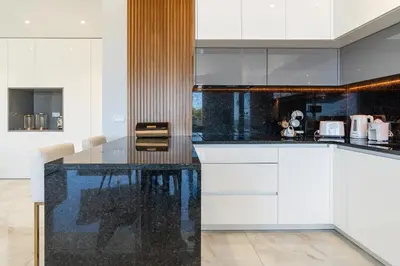 a kitchen with white cabinets and a black counter top at El Dourado House in Caniço