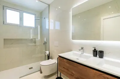 a bathroom with a sink and a toilet and a mirror at El Dourado House in Caniço