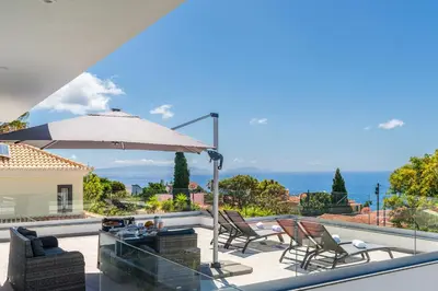 a patio with a table and chairs and an umbrella at El Dourado House in Caniço