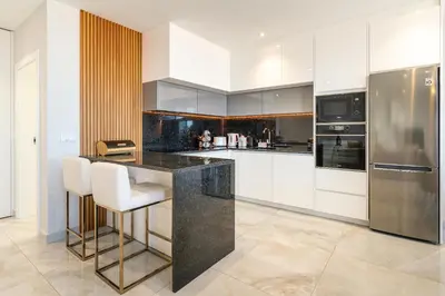 a kitchen with a black counter and white cabinets at El Dourado House in Caniço