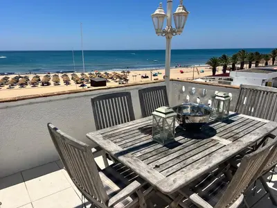 a wooden table with chairs and a view of the beach at STUNNING BEACH PENTHOUSE Best Views In Luz in Luz