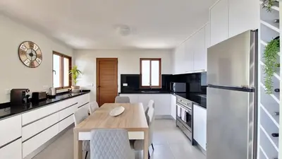 a kitchen with white cabinets and a wooden table at Casa Clementine by LovelyStay in Funchal