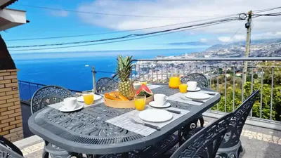 a table on a balcony with a view of the ocean at Casa Clementine by LovelyStay in Funchal