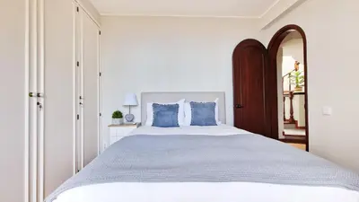 a white bedroom with a large bed with blue pillows at Casa Clementine by LovelyStay in Funchal