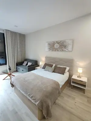 a white bedroom with a large bed and a couch at Serenity Studio in Caniço