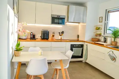 a kitchen with white cabinets and a table and chairs at The Luzia House - sunny 4BR Villa with gardens, terraces, AC, on-site parking in Funchal