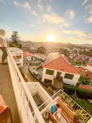 a woman standing on a balcony looking at the sunset at The Luzia House - sunny 4BR Villa with gardens, terraces, AC, on-site parking in Funchal