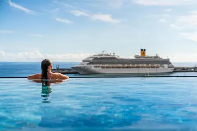 a woman in a pool with a cruise ship in the background at Savoy Insular VI by An Island Apart in Funchal
